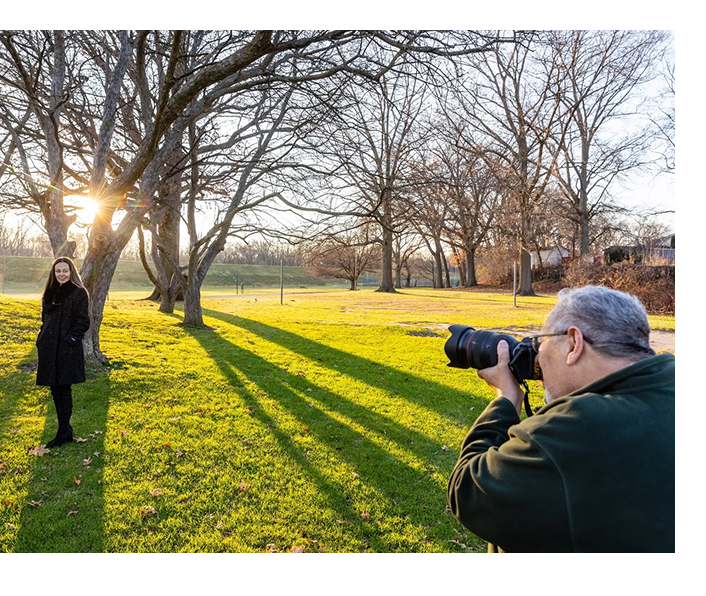 A man taking a picture of another person in the park.